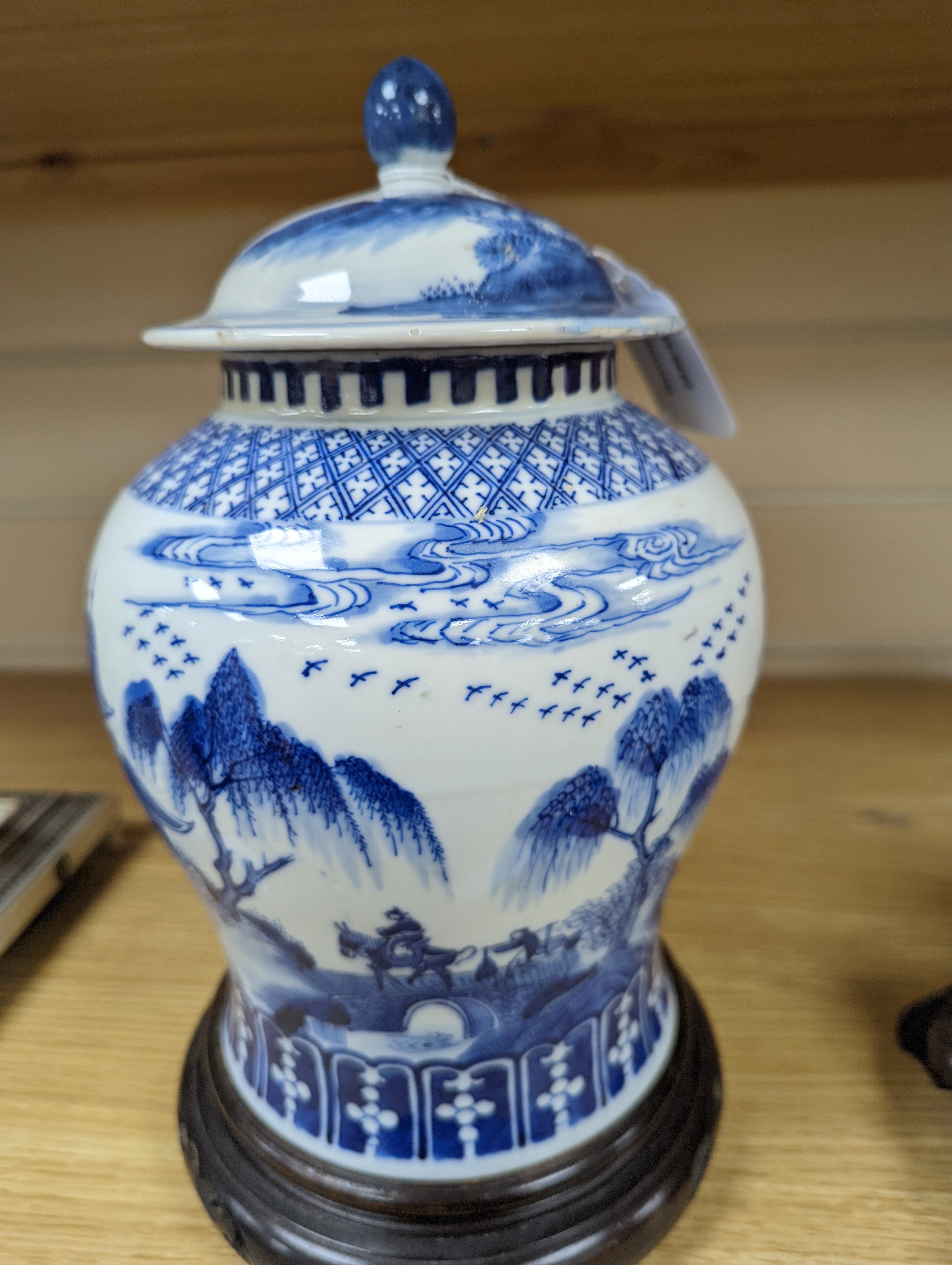 A late 19th / early 20th century Chinese blue and white landscape jar and cover, wood stand 30cm total height